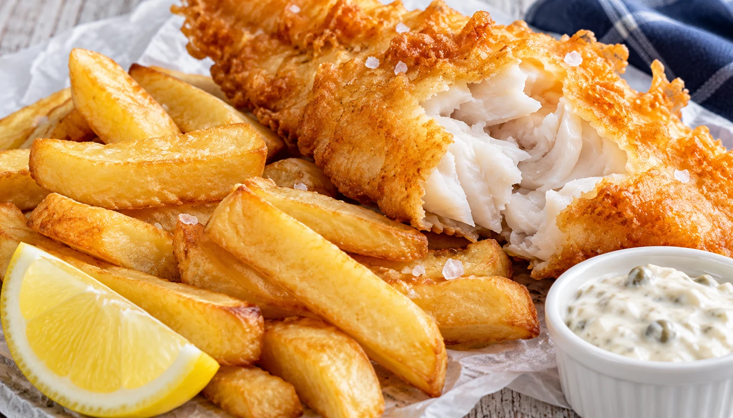 Golden battered fish with chips, lemon and tartar sauce